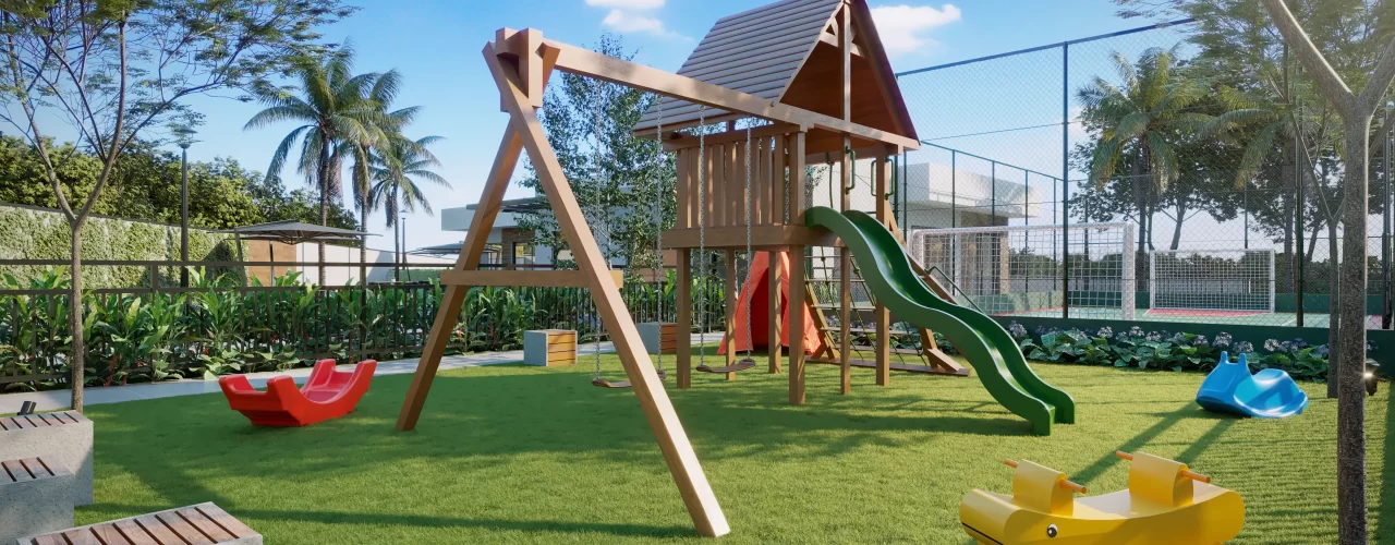 Playground infantil em gramado com estrutura de madeira, escorregador verde, balanços e brinquedos de mola coloridos, ao lado de quadra esportiva cercada por vegetação.
